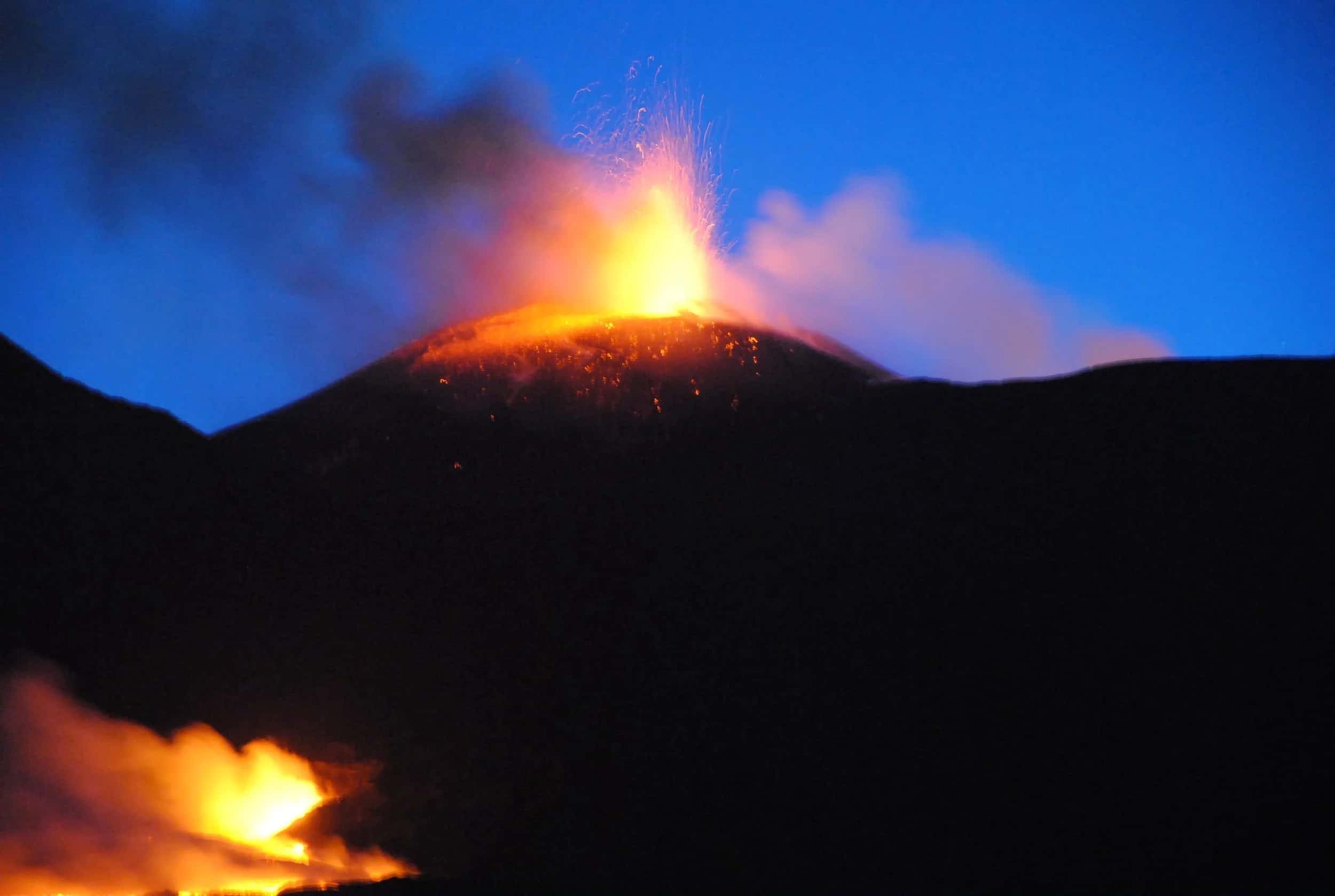 Etna erupting at night: a lava fountain from the crater and an incandescent flow