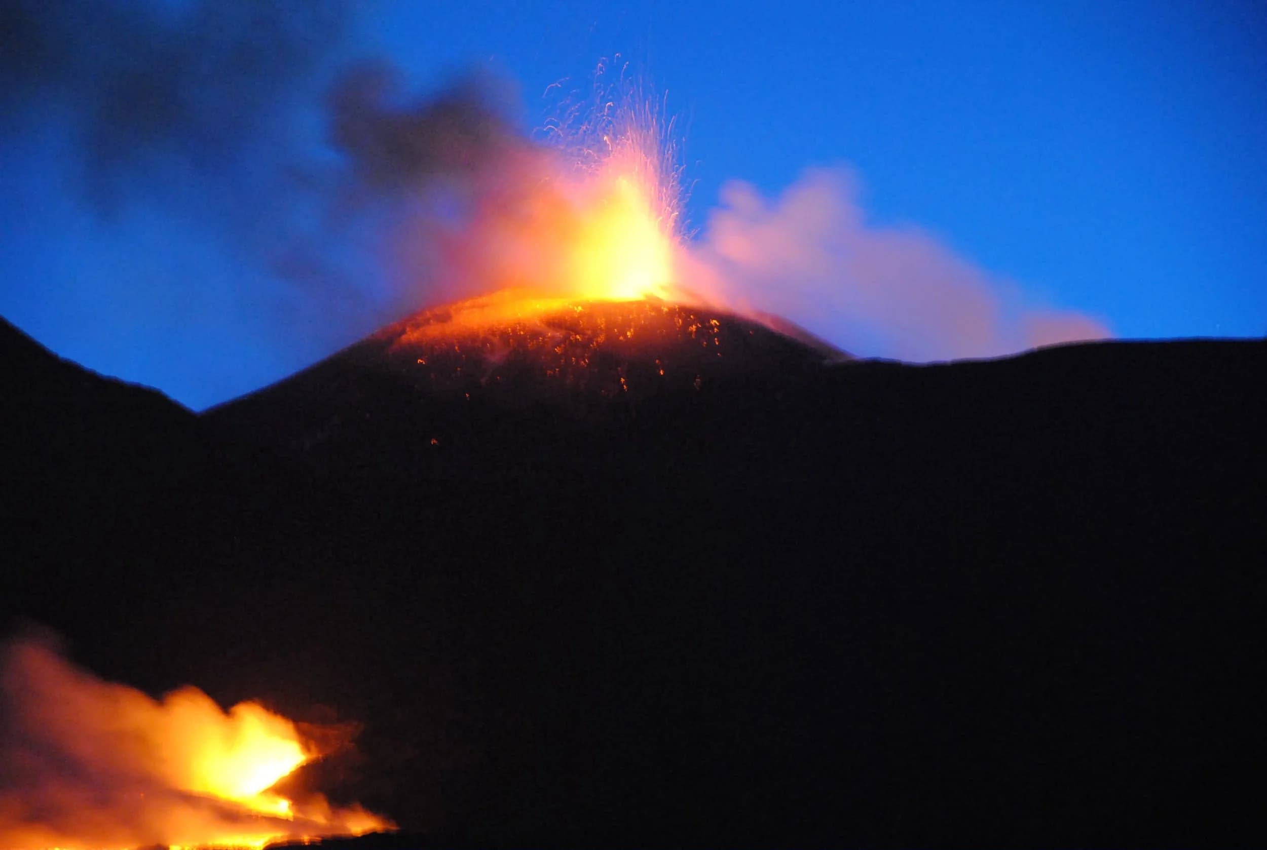 Eruzione notturna dell'Etna: fontana di lava dal cratere e colata incandescente