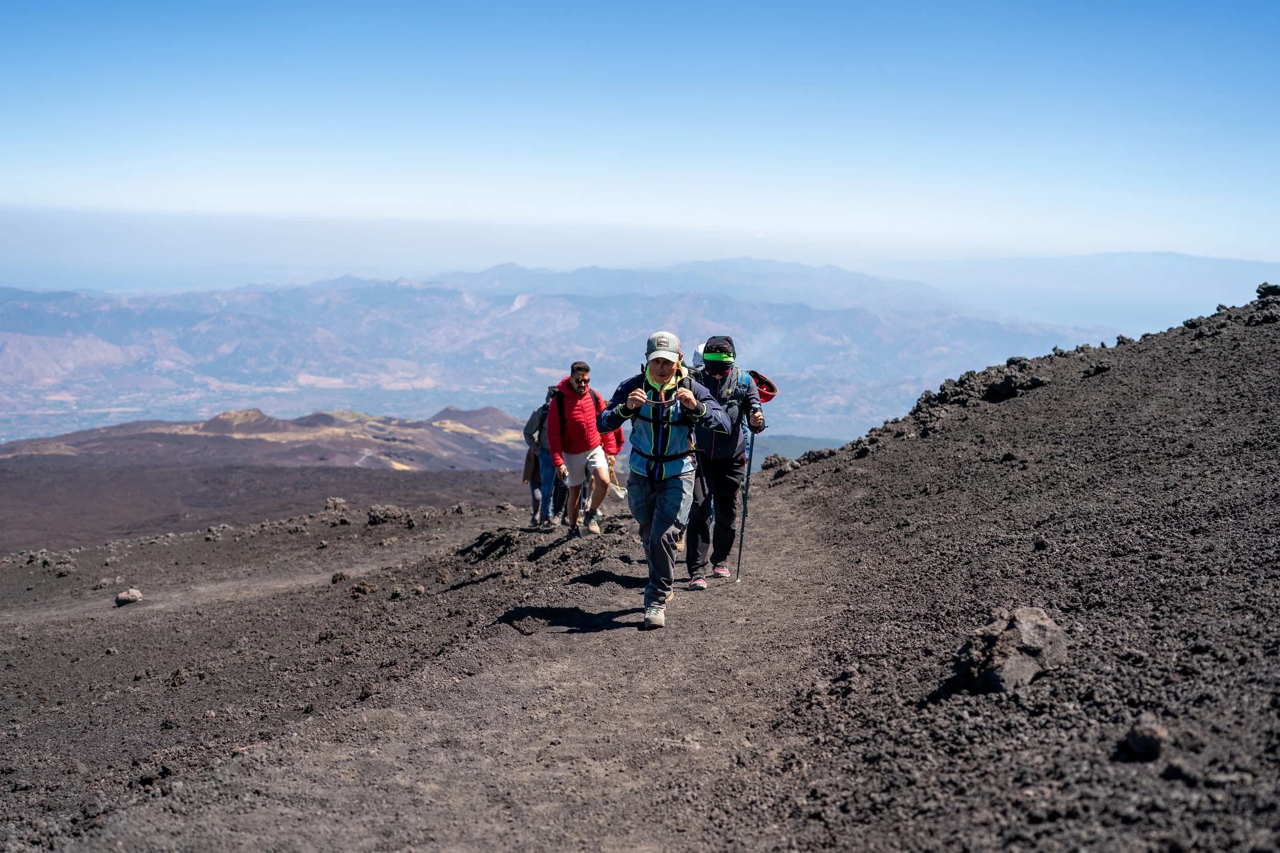 Hikers climbing the ash trail, with the Ionian coast on the horizon